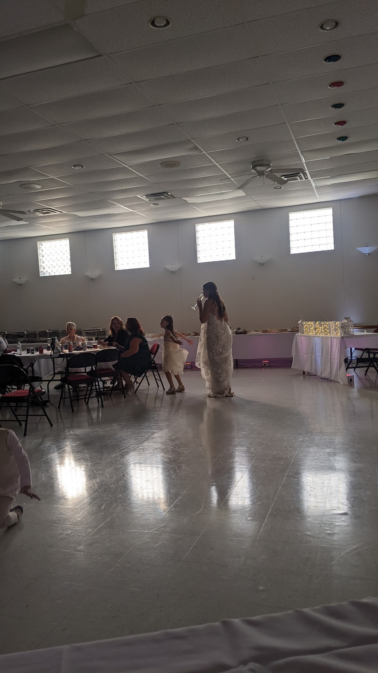 Indoor banquet hall with guests seated at tables and a speaker standing near the center.