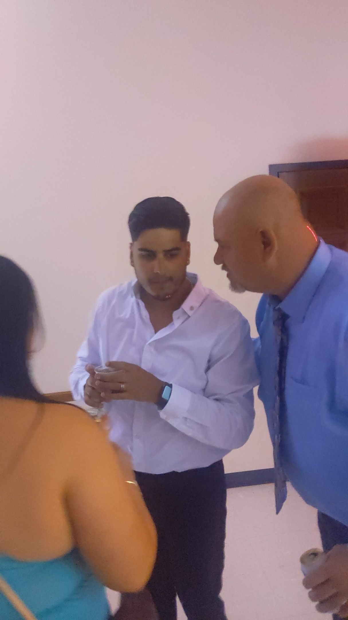 Three people converse in a hallway, with one man gesturing while others listen.
