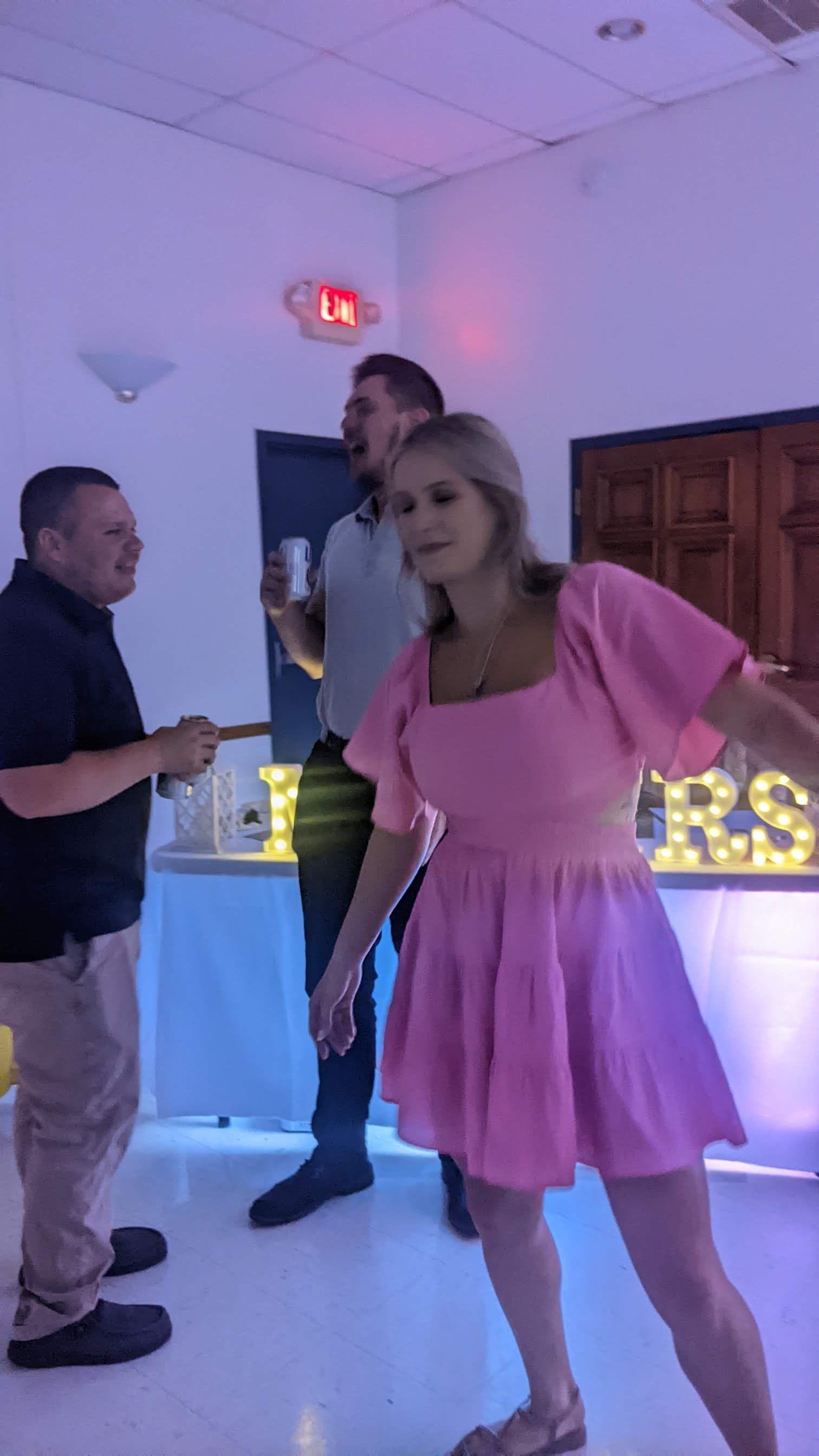 Woman in pink dress posing at a party with lit letters in the background