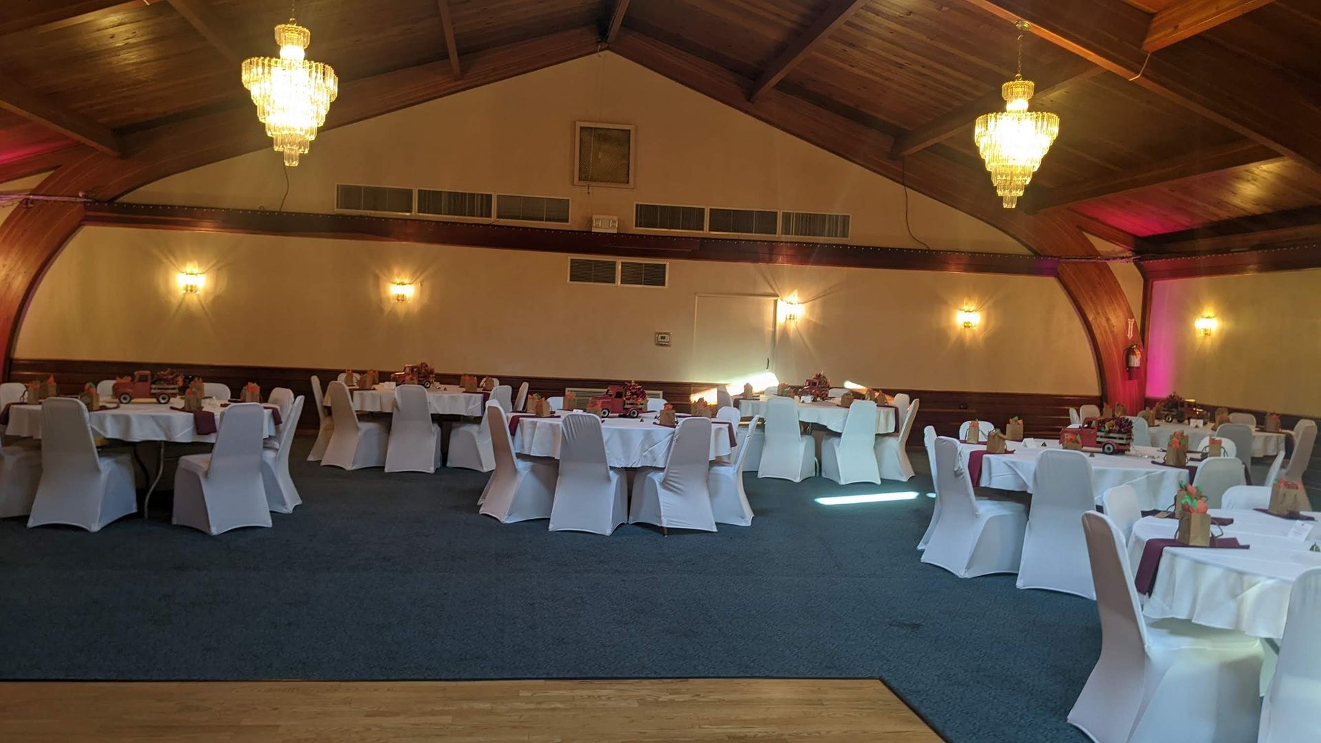 Banquet hall with round tables, white chair covers, and warm hanging lights