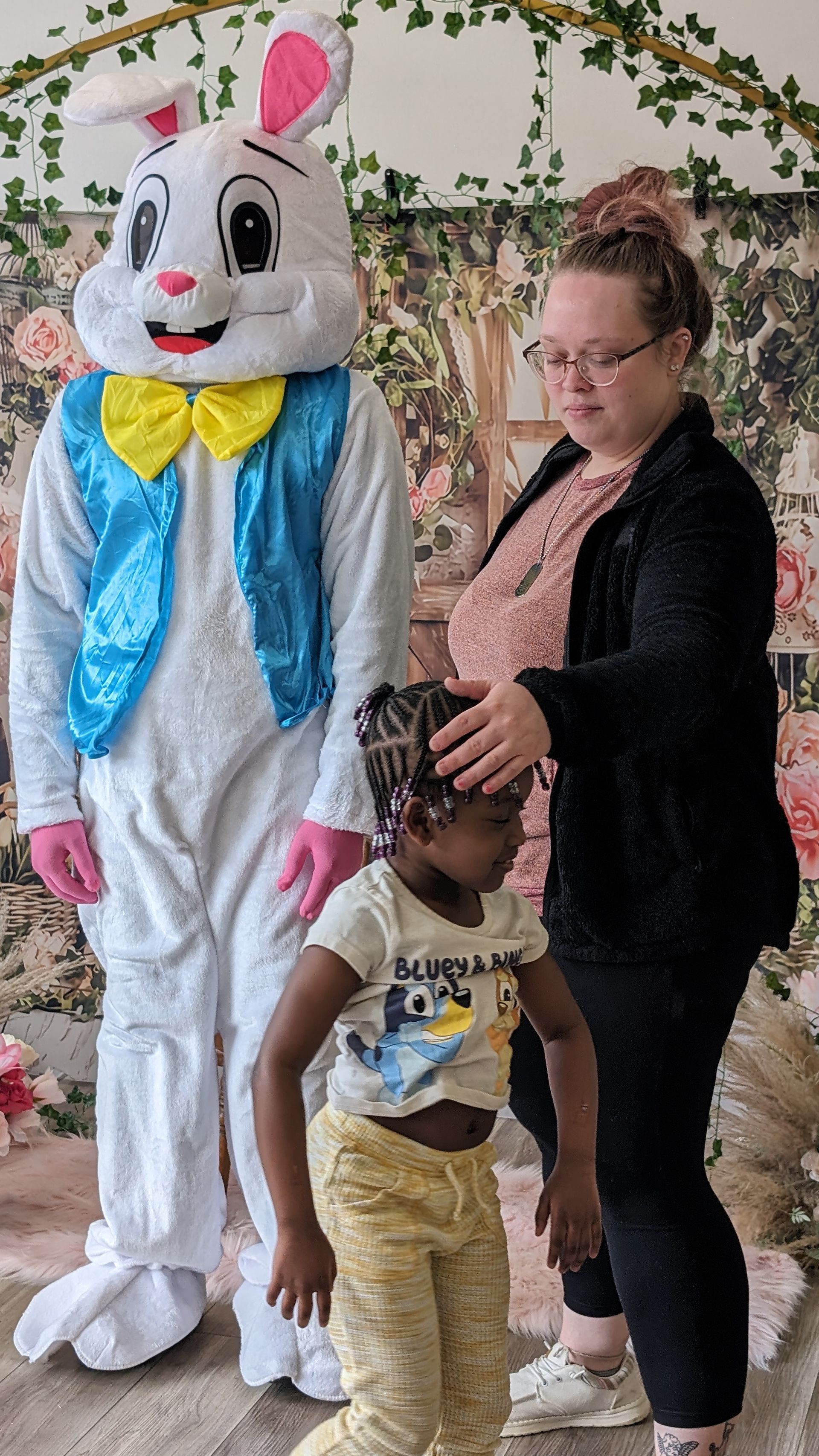 Person and child posing with a person in a white bunny costume at an outdoor event.