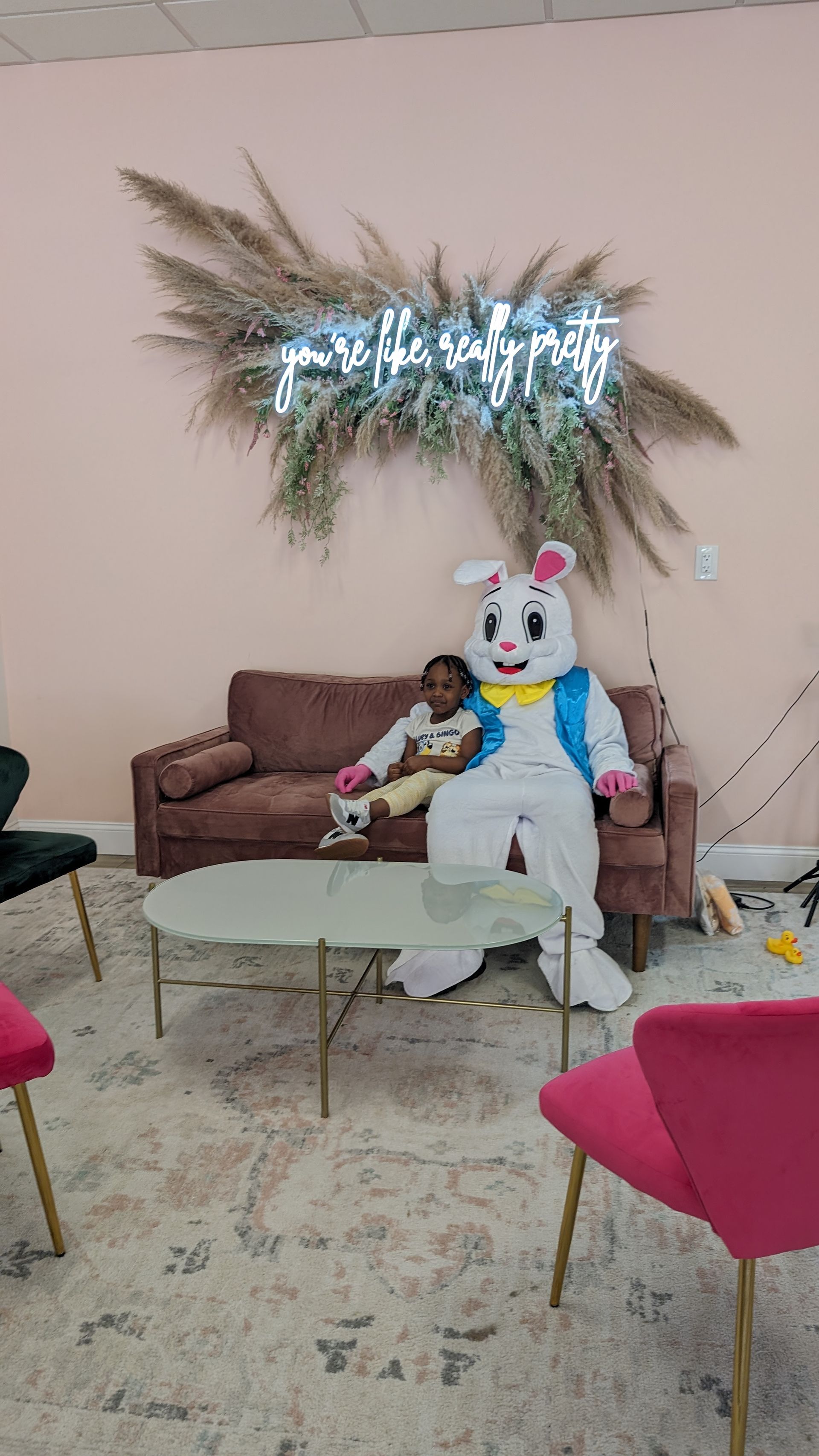 Person in a white bunny costume seated in a decorated living room with a sofa and coffee table.