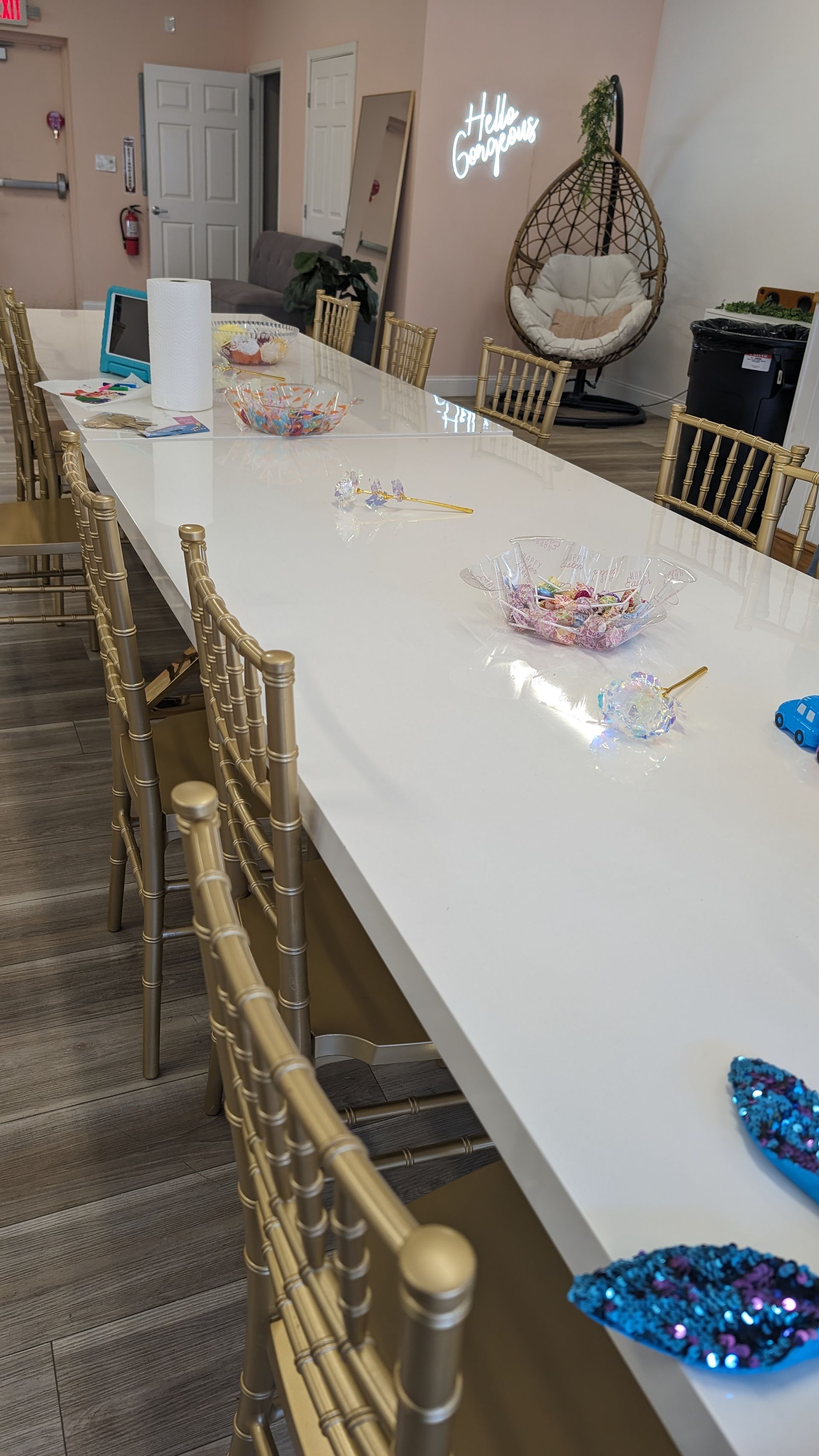 Long white table with gold chairs and scattered party decorations in a room