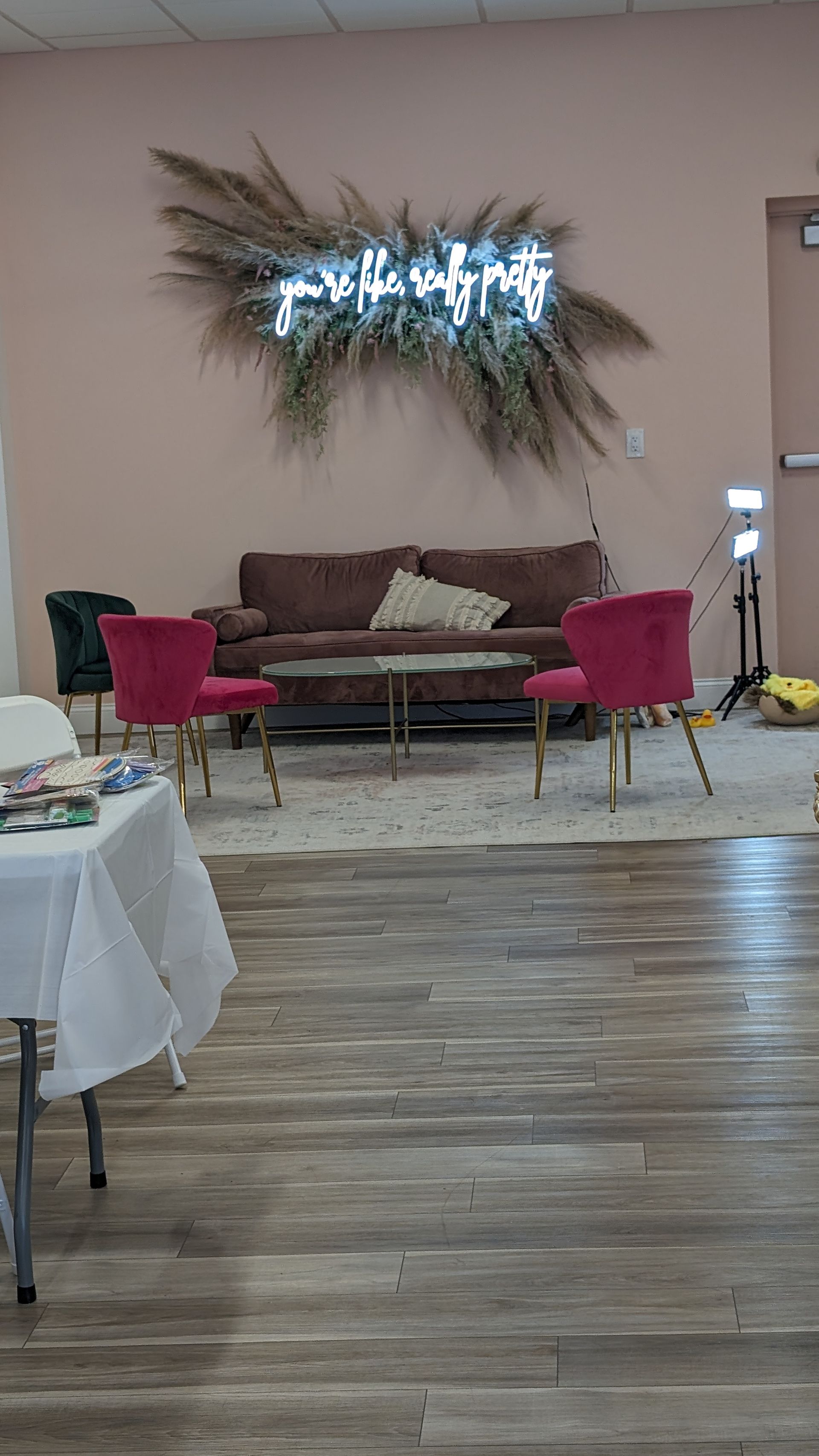 Lounge area with beige sofa, pink chairs, wood floor, and a wall light centerpiece.