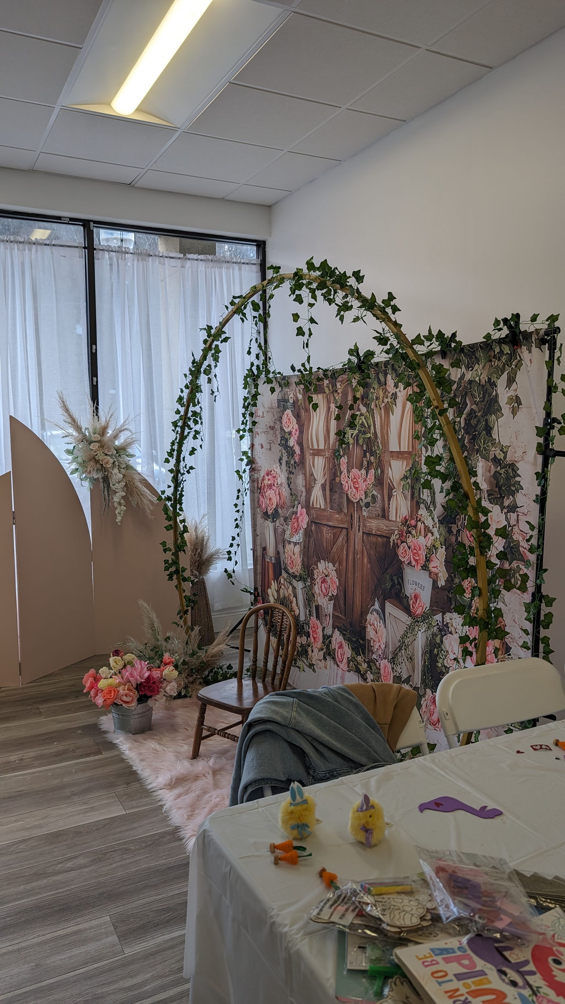 Decorated indoor event space with floral arch, pink backdrop, and table setting for a celebration