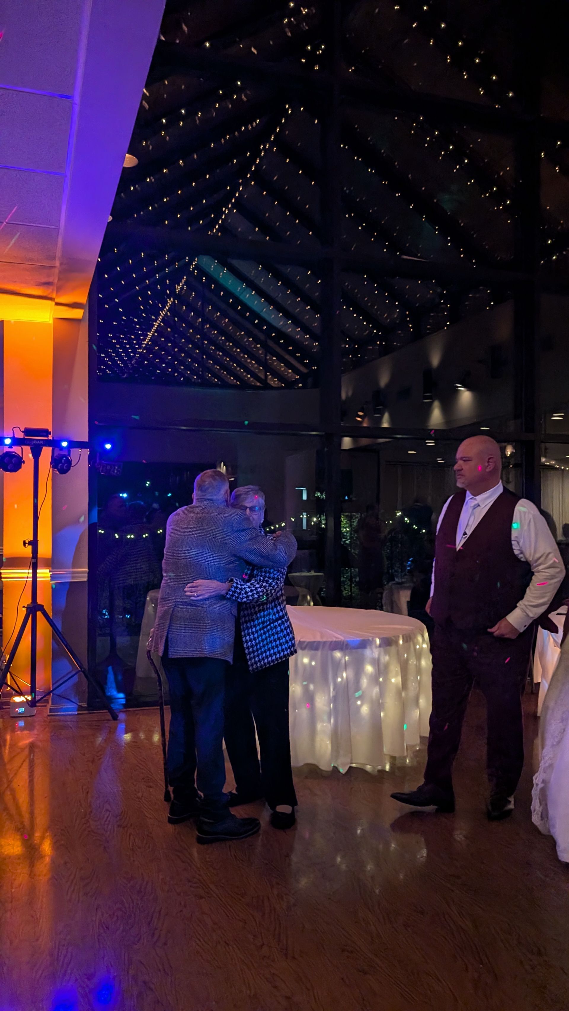 Guests chatting beside a glowing round table in a dimly lit event hall with purple and gold lighting