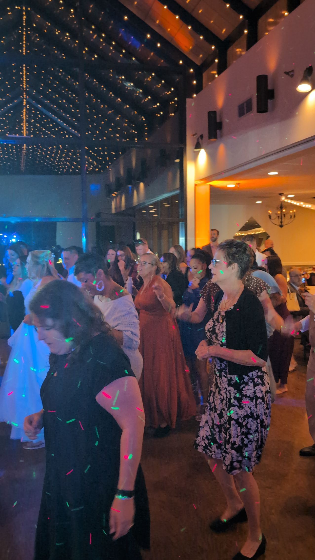 Guests dancing at a warmly lit indoor event with string lights overhead.