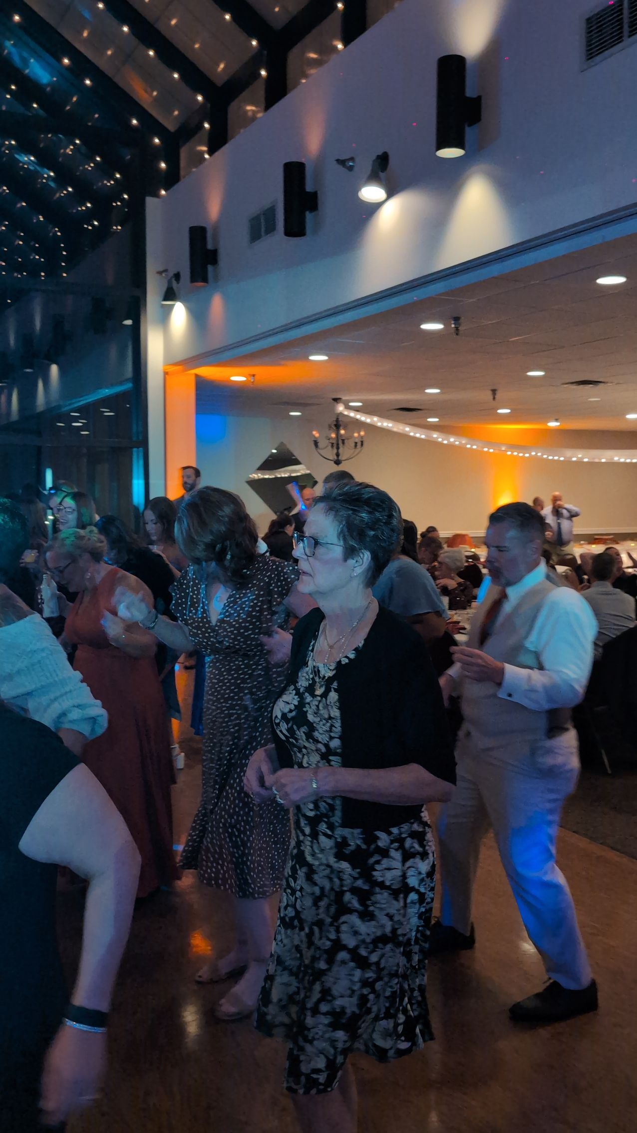 People dancing at an indoor party under warm lights in a large venue