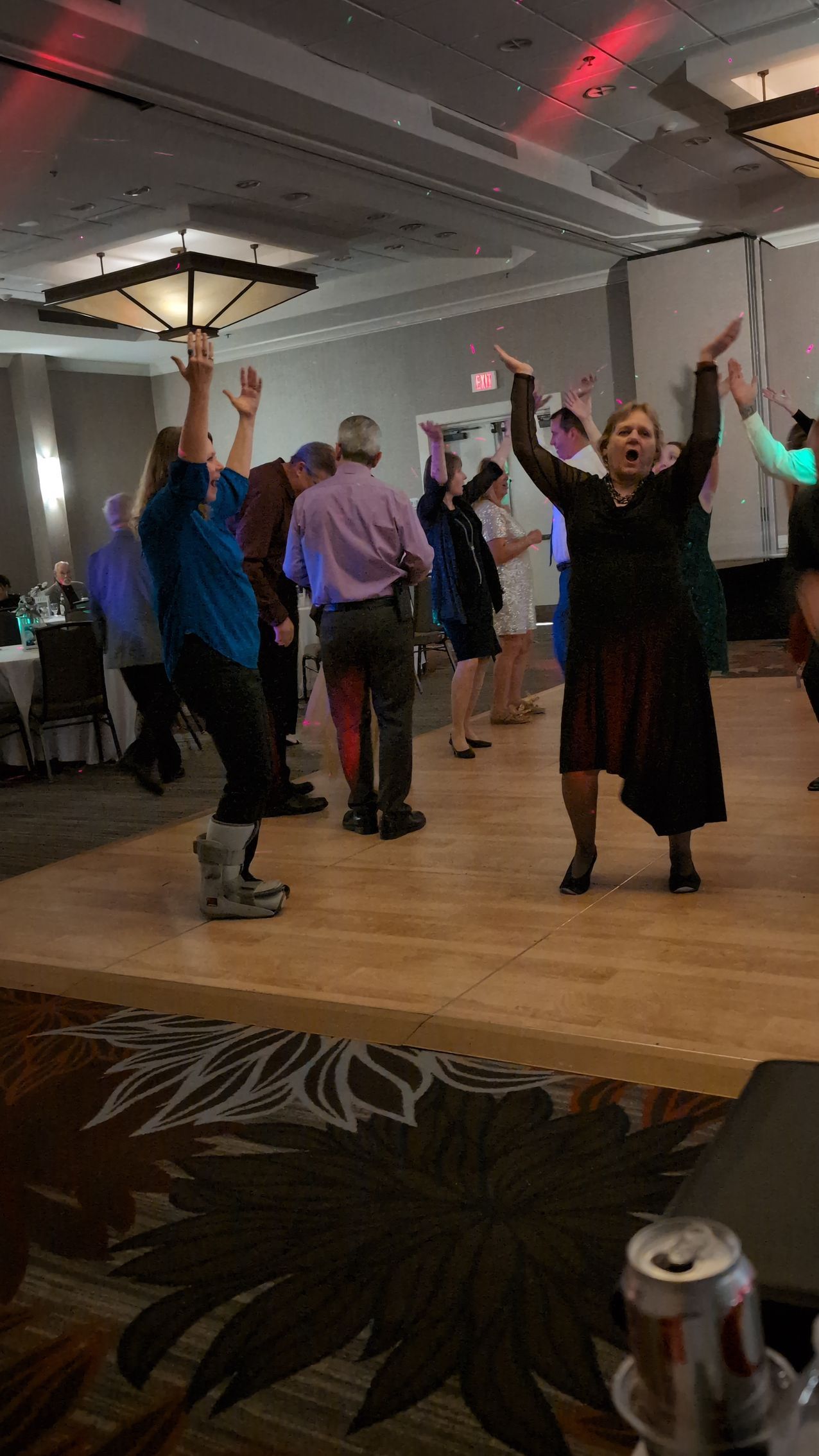 People dancing with arms raised in a banquet hall during a group event