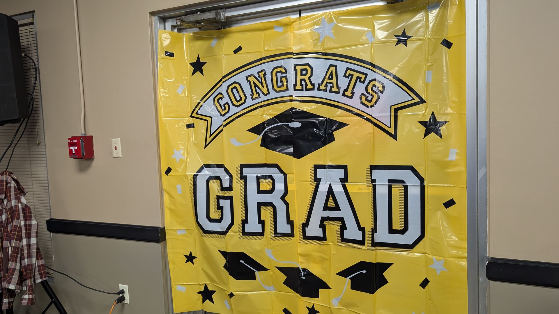 Yellow “Congrats Grad” banner with black stars and graduation cap in a hallway