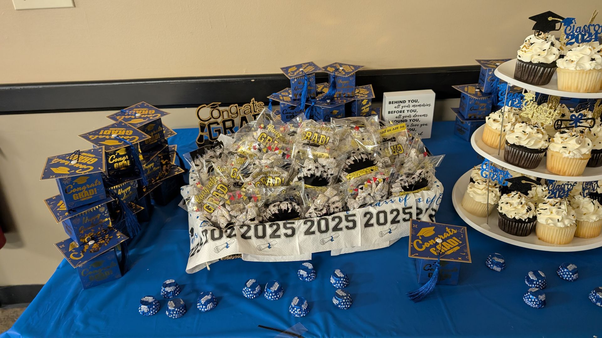 Blue and silver 2025 graduation candy display with cupcakes and treats on a table