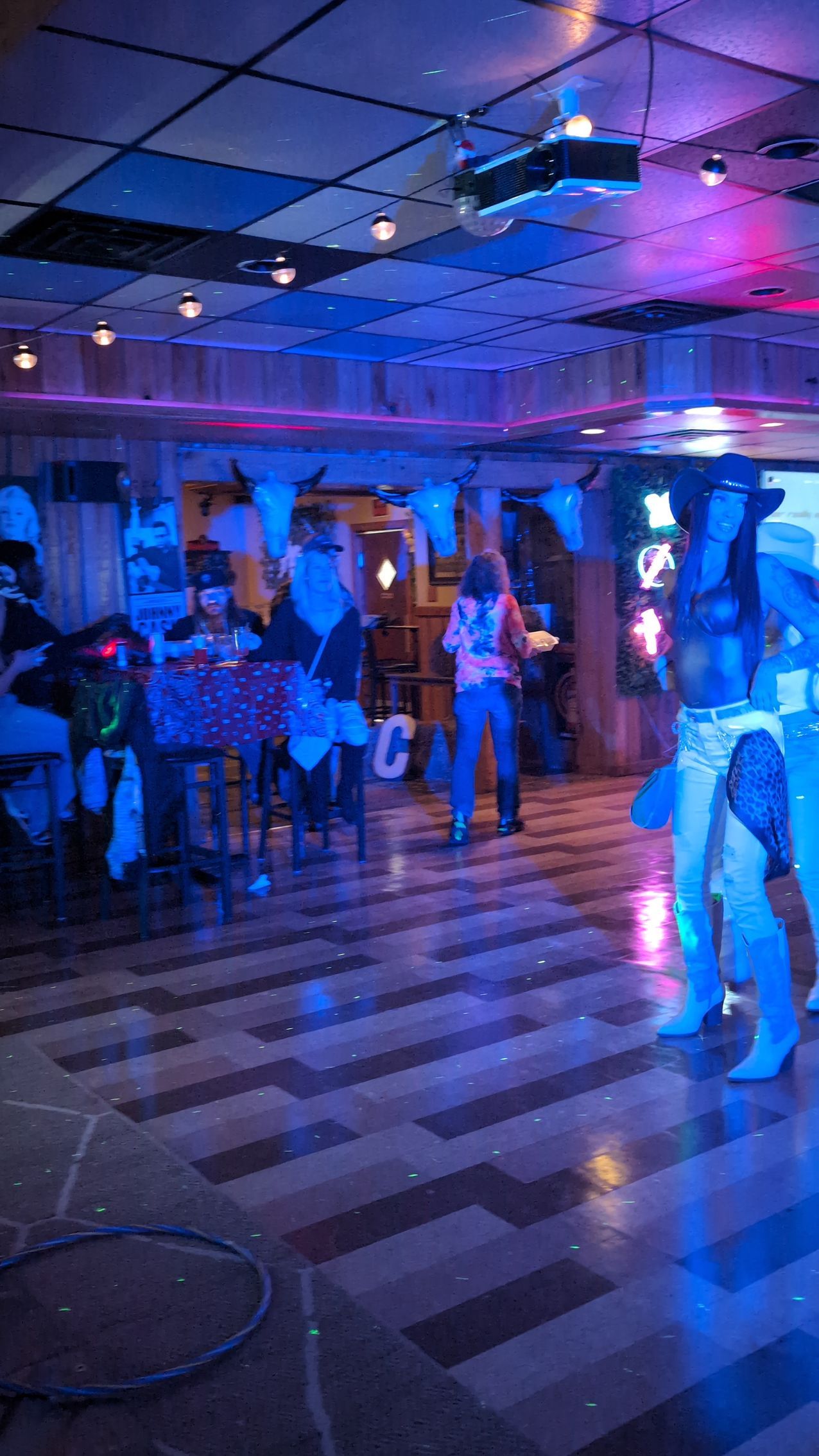 People dancing in a dimly lit club with blue and purple lights and striped flooring