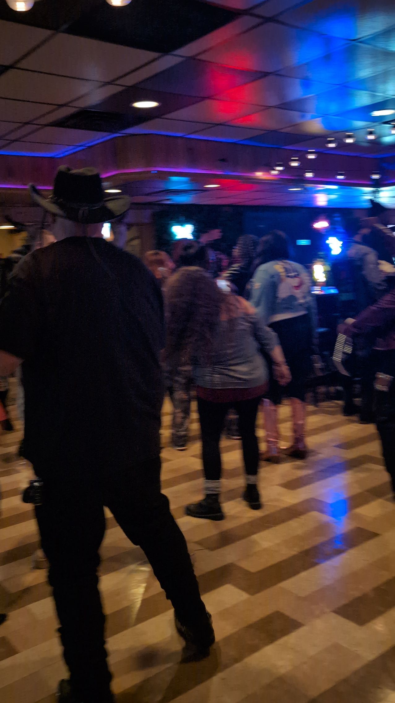 People standing and dancing in a dimly lit nightclub with blue and pink lights
