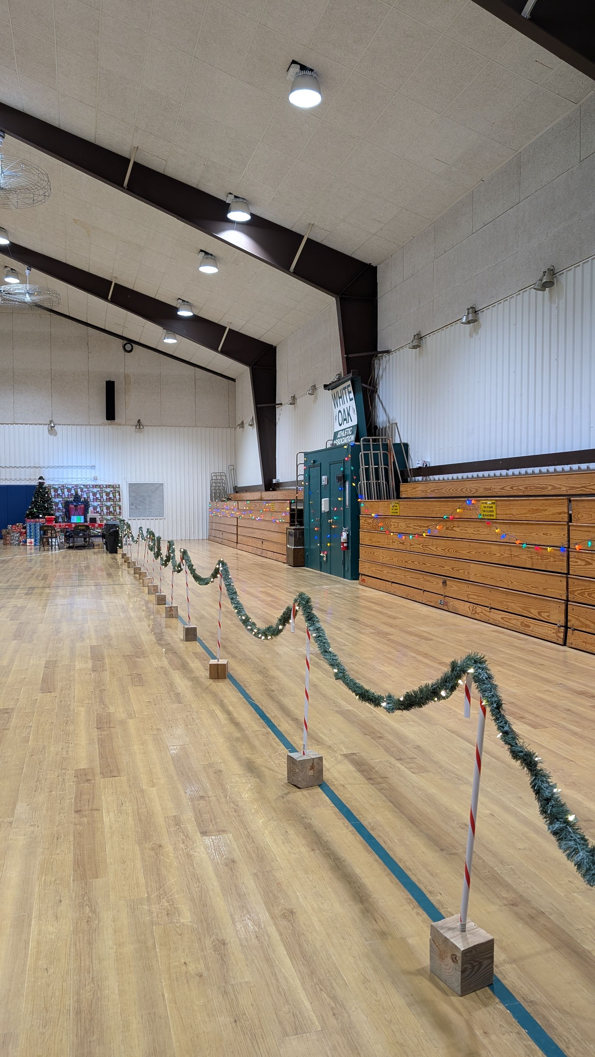 Indoor gymnasium with wooden floor, rope barriers, and stacked mats along the wall