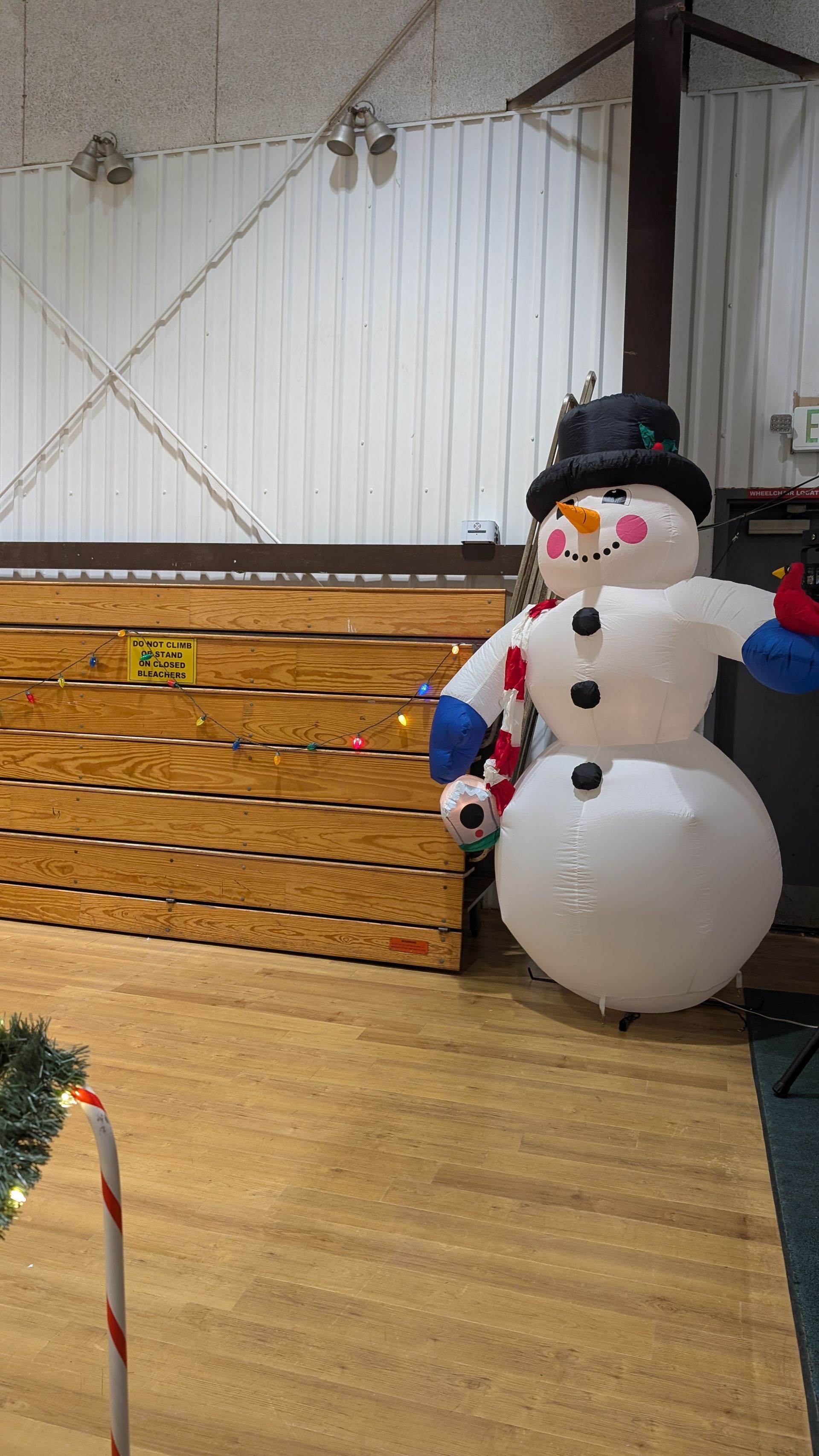 Snowman decoration beside a wooden stage in an indoor hall
