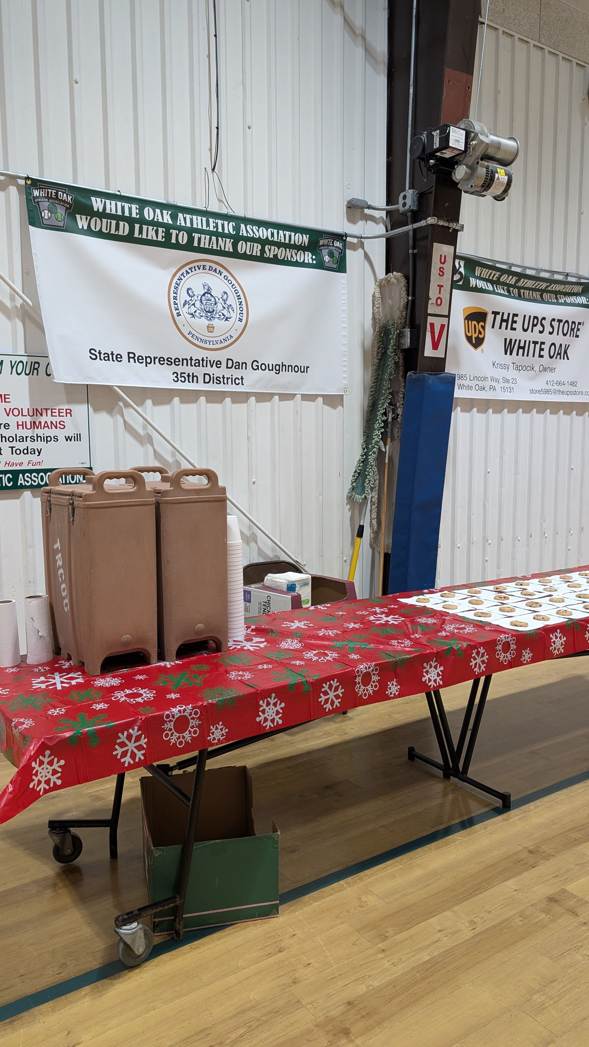 Indoor hall with long table, banners, boxes, and a mounted camera on a blue pole