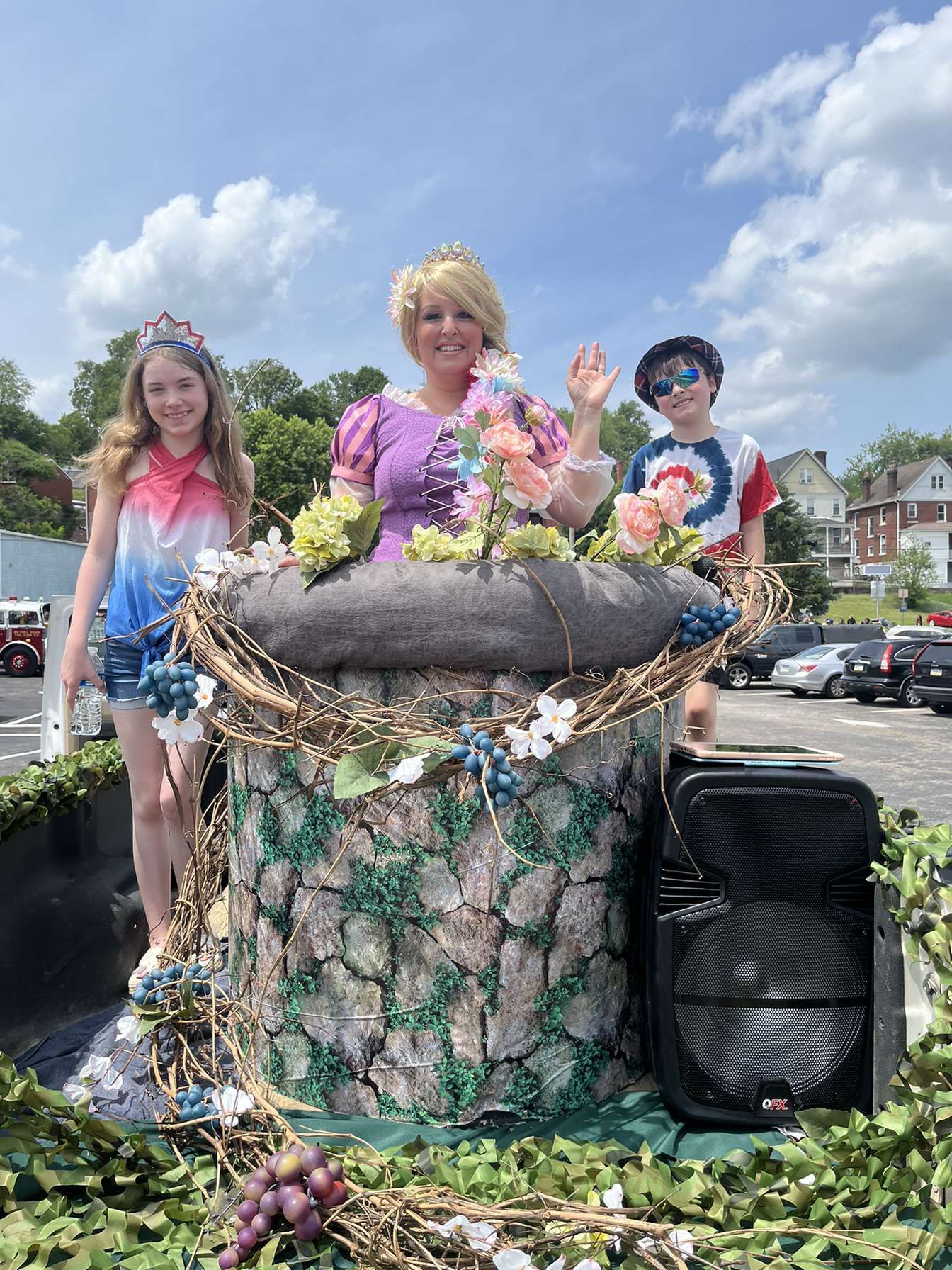 Children posing on a decorated float with flowers and greenery in a street parade