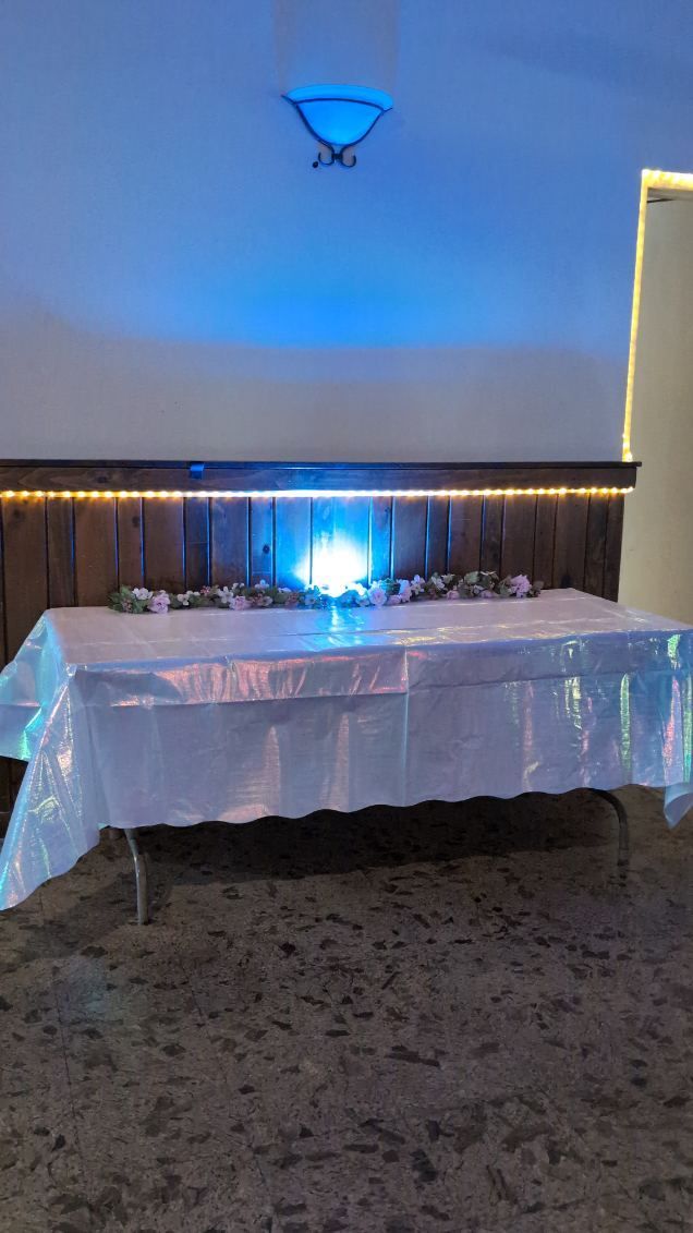 Blue-lit banquet table with white tablecloth and decorations in a dim indoor event room