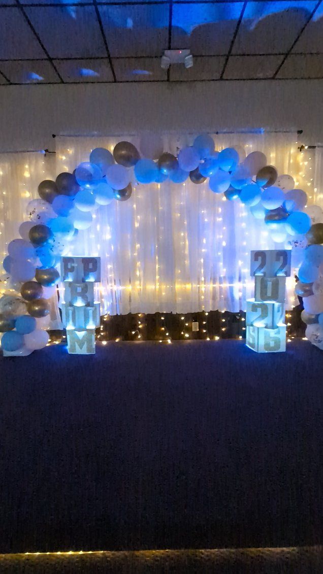 Blue and white balloon arch with fairy lights framing a decorated stage backdrop