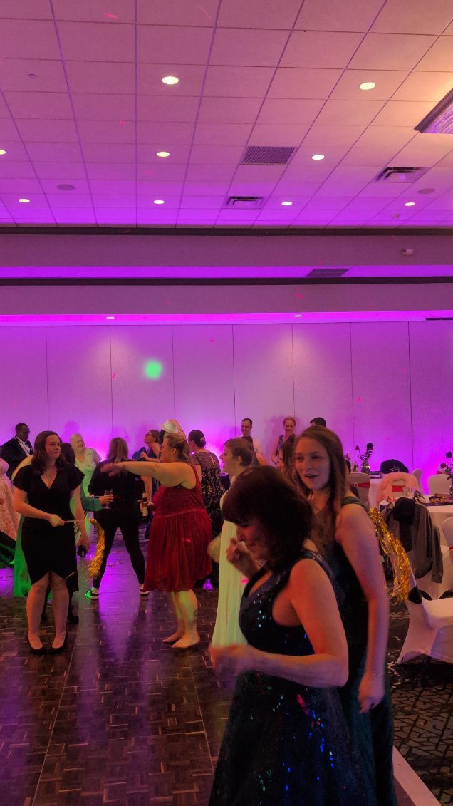People dancing in a purple-lit banquet hall during a social event