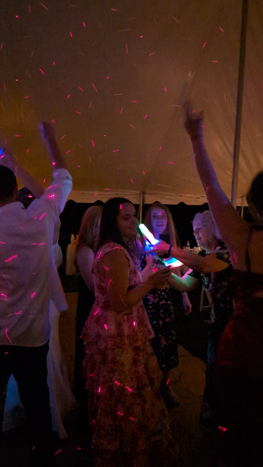 Guests dancing under pink and red disco lights at a lively indoor party