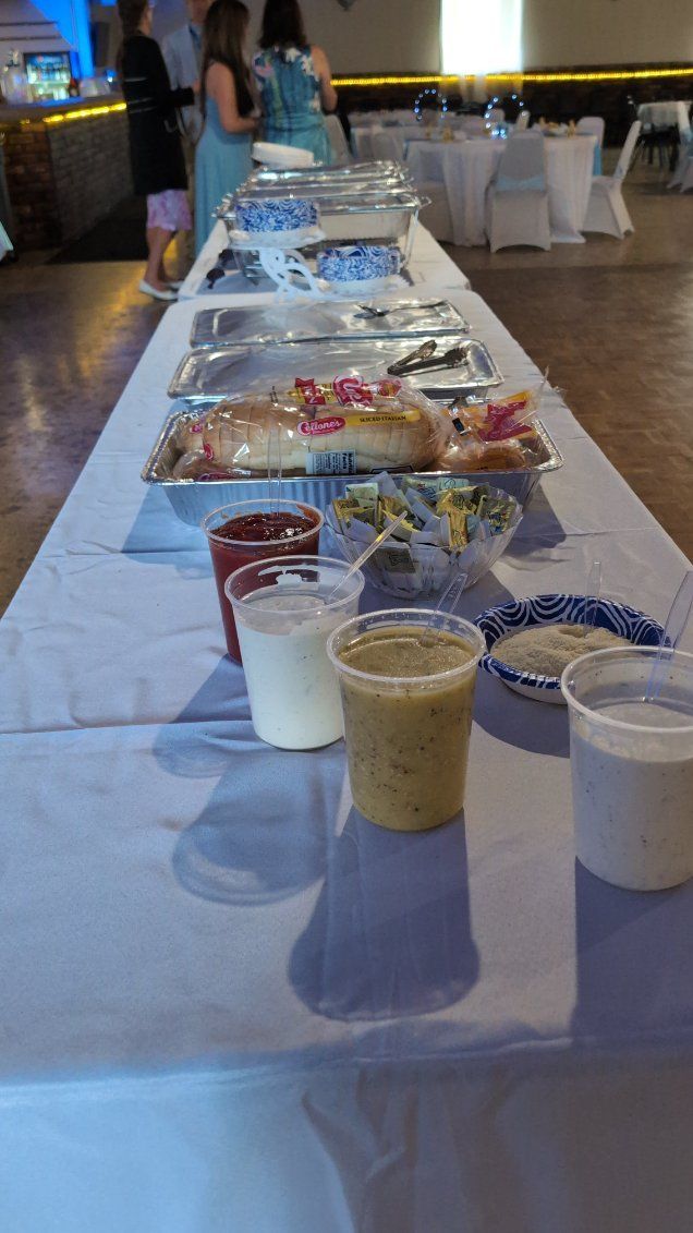 Long banquet table with covered dishes and small dessert cups in a decorated hall