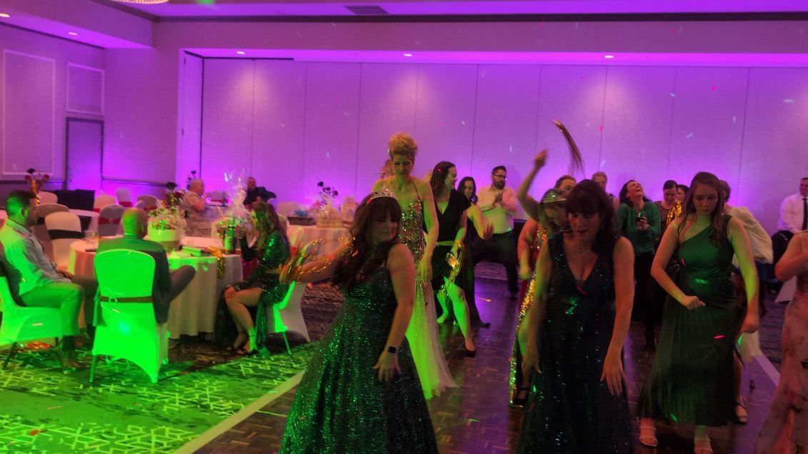 People dancing at a banquet hall with purple and green lighting