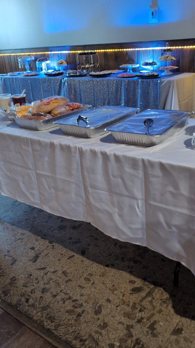 Buffet table with chafing dishes and platters under blue lighting in a banquet room