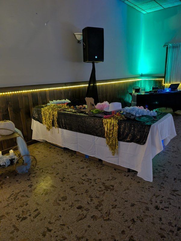 Decorated banquet table with black-and-gold tablecloth, flowers, and speaker at an indoor event venue