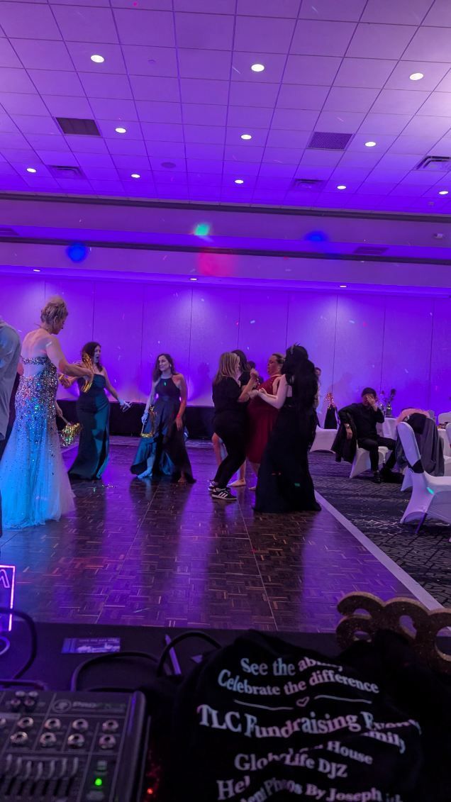 People dancing on a purple-lit ballroom floor at a formal event.