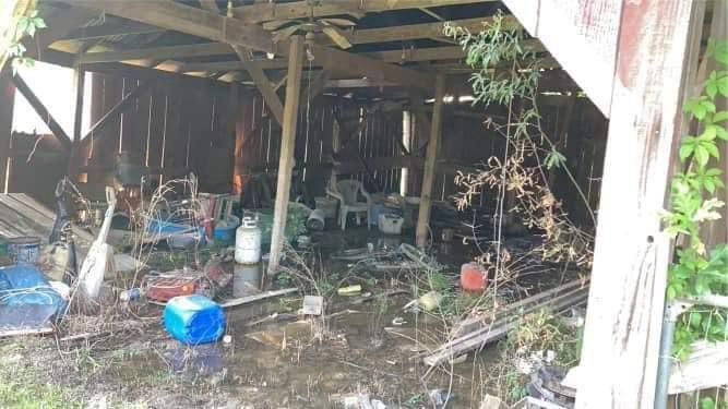 A barn filled with lots of junk and a blue cooler.