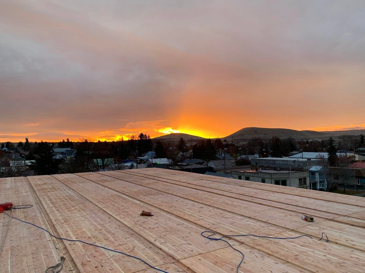 A sunset over a city with a wooden roof in the foreground.