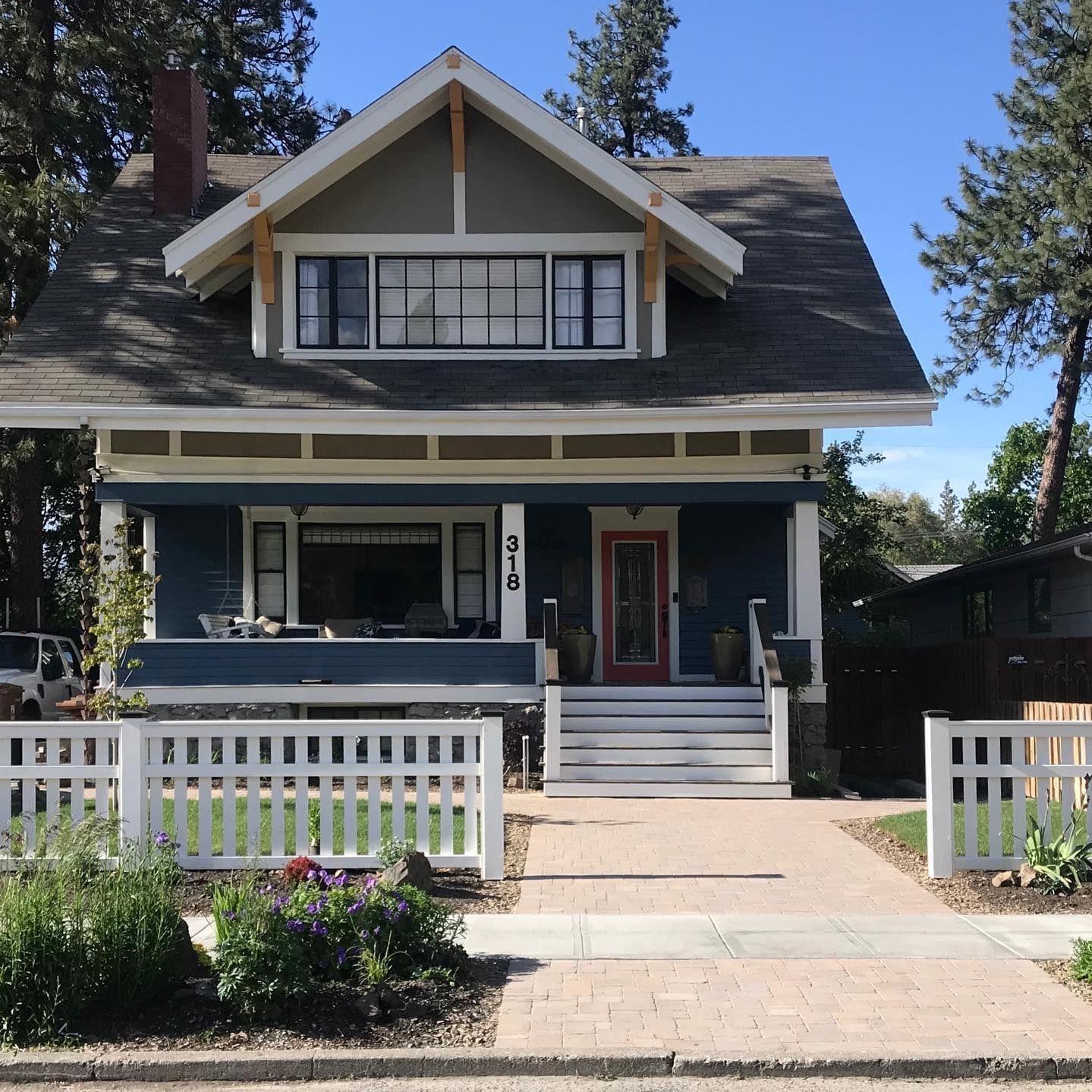 A blue house with a white fence and a red door