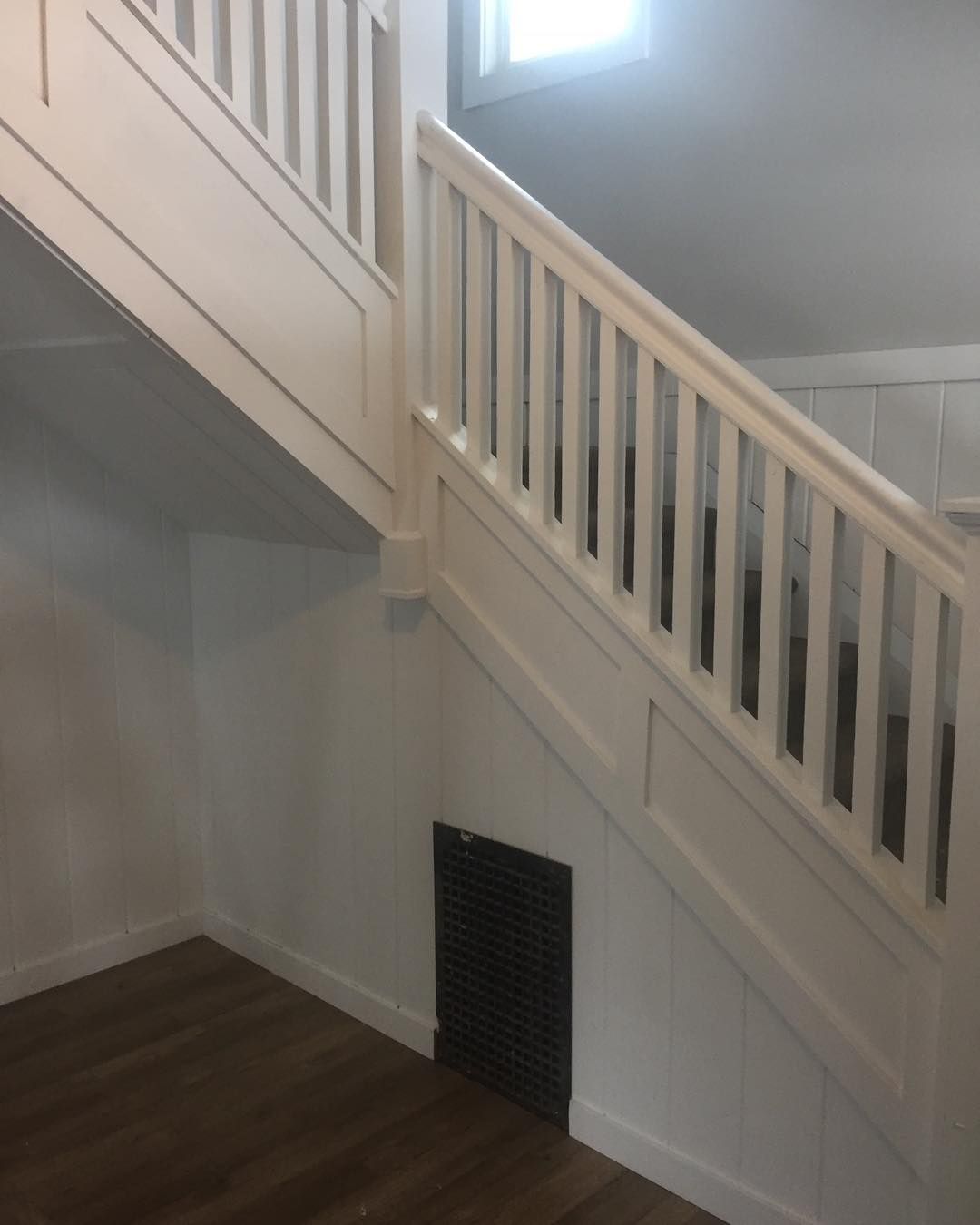 A white staircase with a wooden railing in an empty room