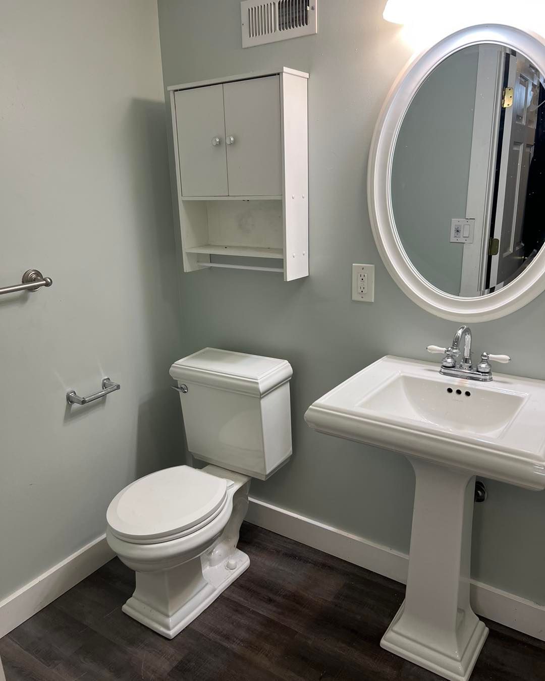A bathroom with a toilet , sink and mirror.
