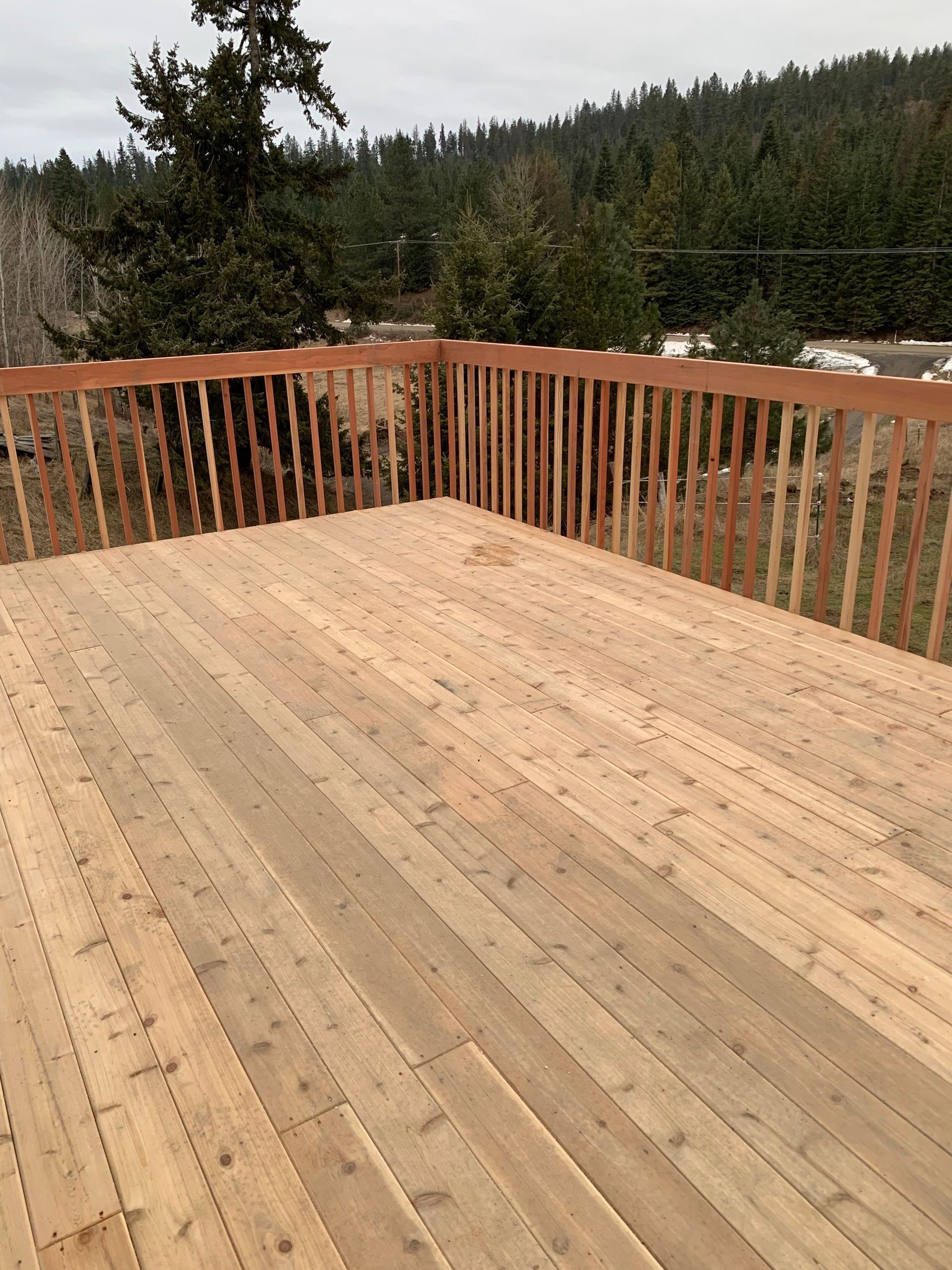 A wooden deck with a railing and trees in the background