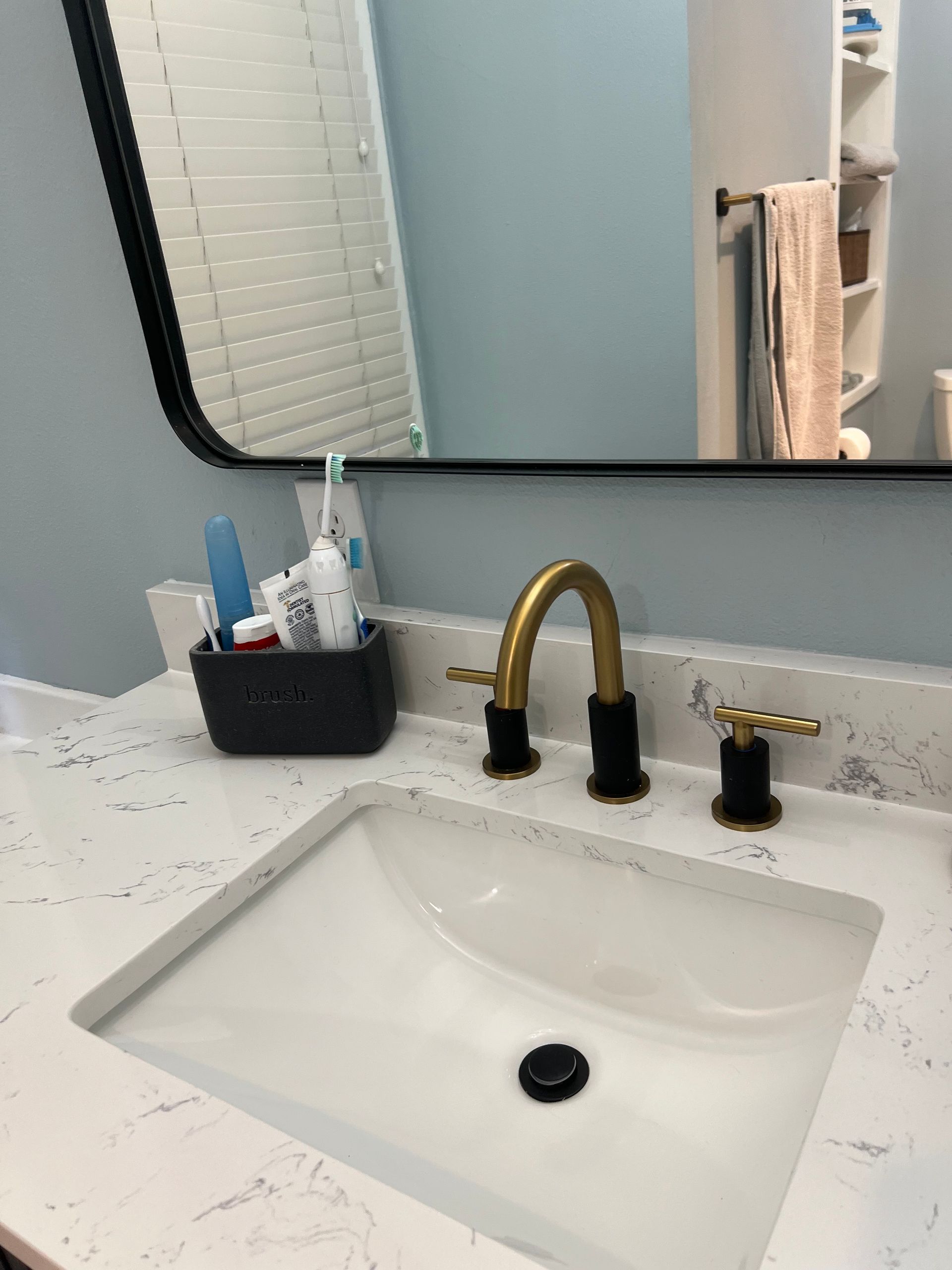 A bathroom sink with a mirror above it and a toothbrush holder.