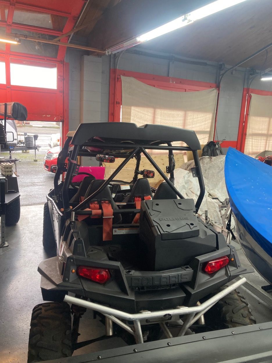 Black UTV with roll cage parked inside a garage, open door in background.