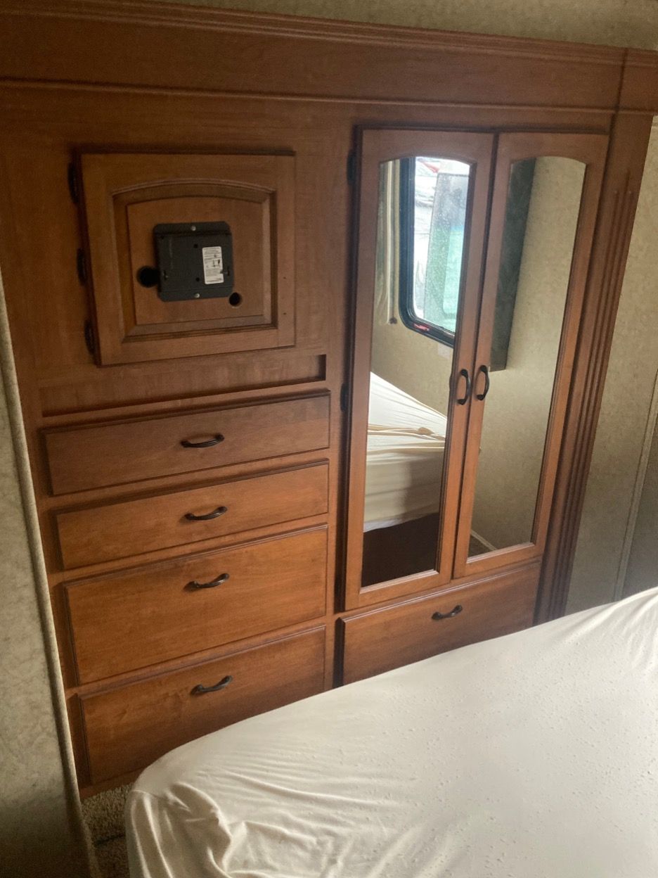 Bedroom wardrobe with drawers, mirrored doors, and a small safe, in an RV.