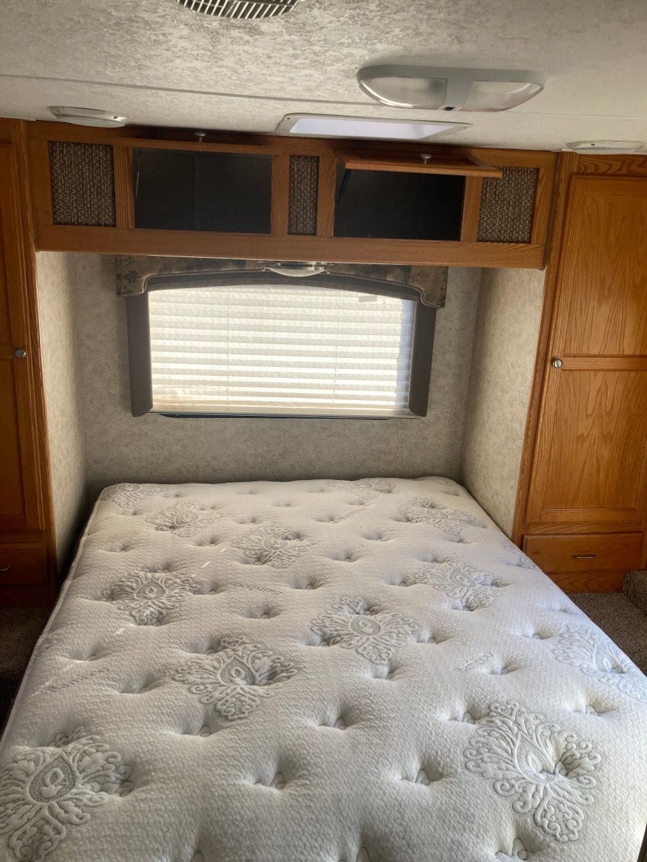 Bedroom in a recreational vehicle: bed, window, storage cabinets.