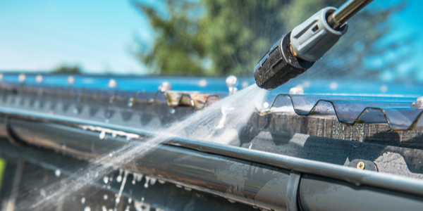 Spring Rain Gutters Cleaning Using Pressure Washer. Closeup Photo.
