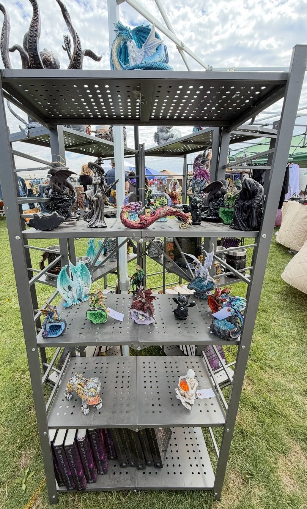 Three-tier metal shelf outdoors, displaying assorted colorful glass figurines and ornaments.
