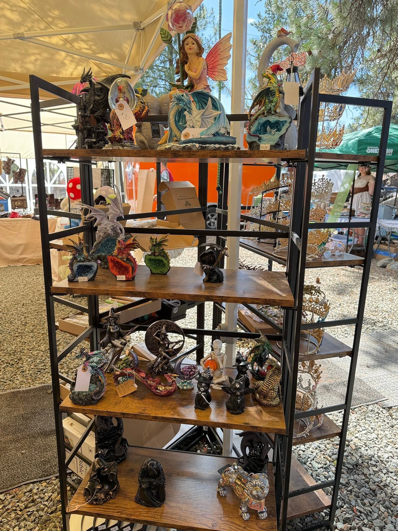 Metal shelving unit displaying small decorative figurines at an outdoor market stall