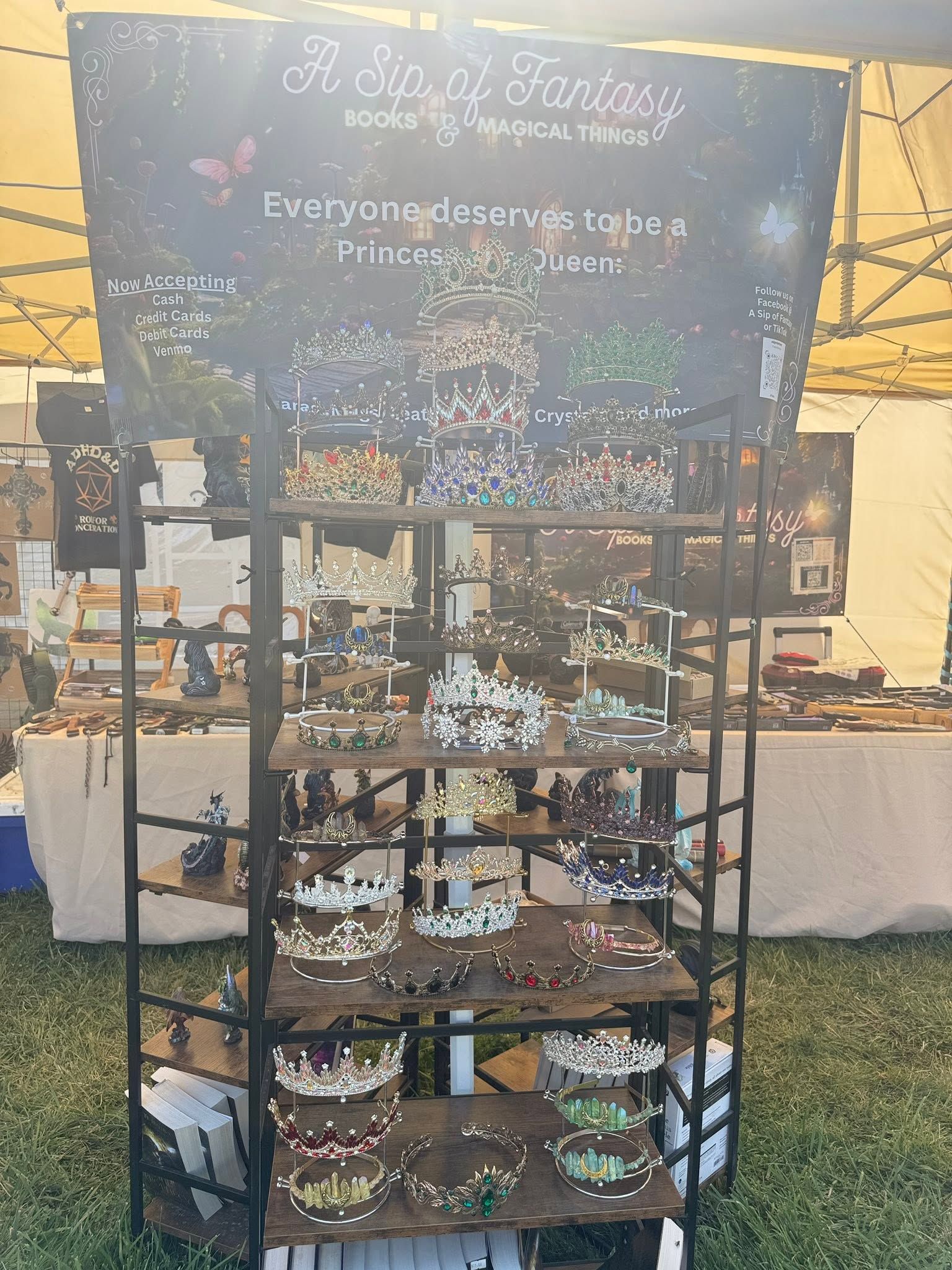 Black metal rack of colorful bracelets and jewelry at a market stall with hanging decor behind it