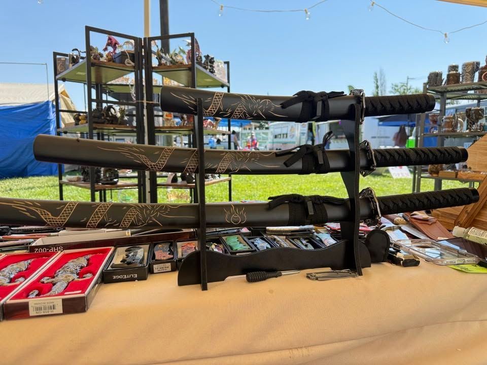 Row of black knives on a tan table at an outdoor market stall