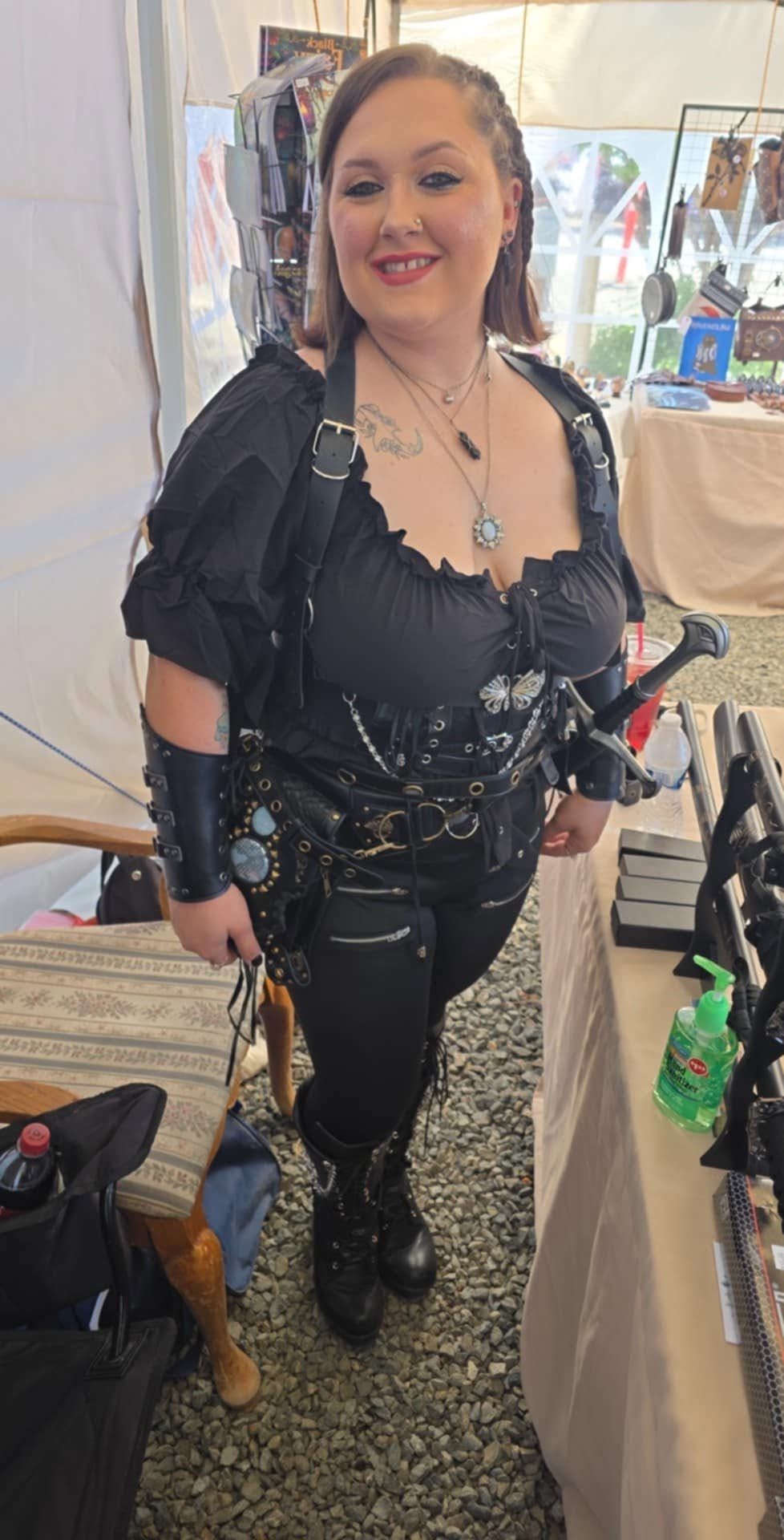 Woman in a black leather outfit smiling at an indoor event booth