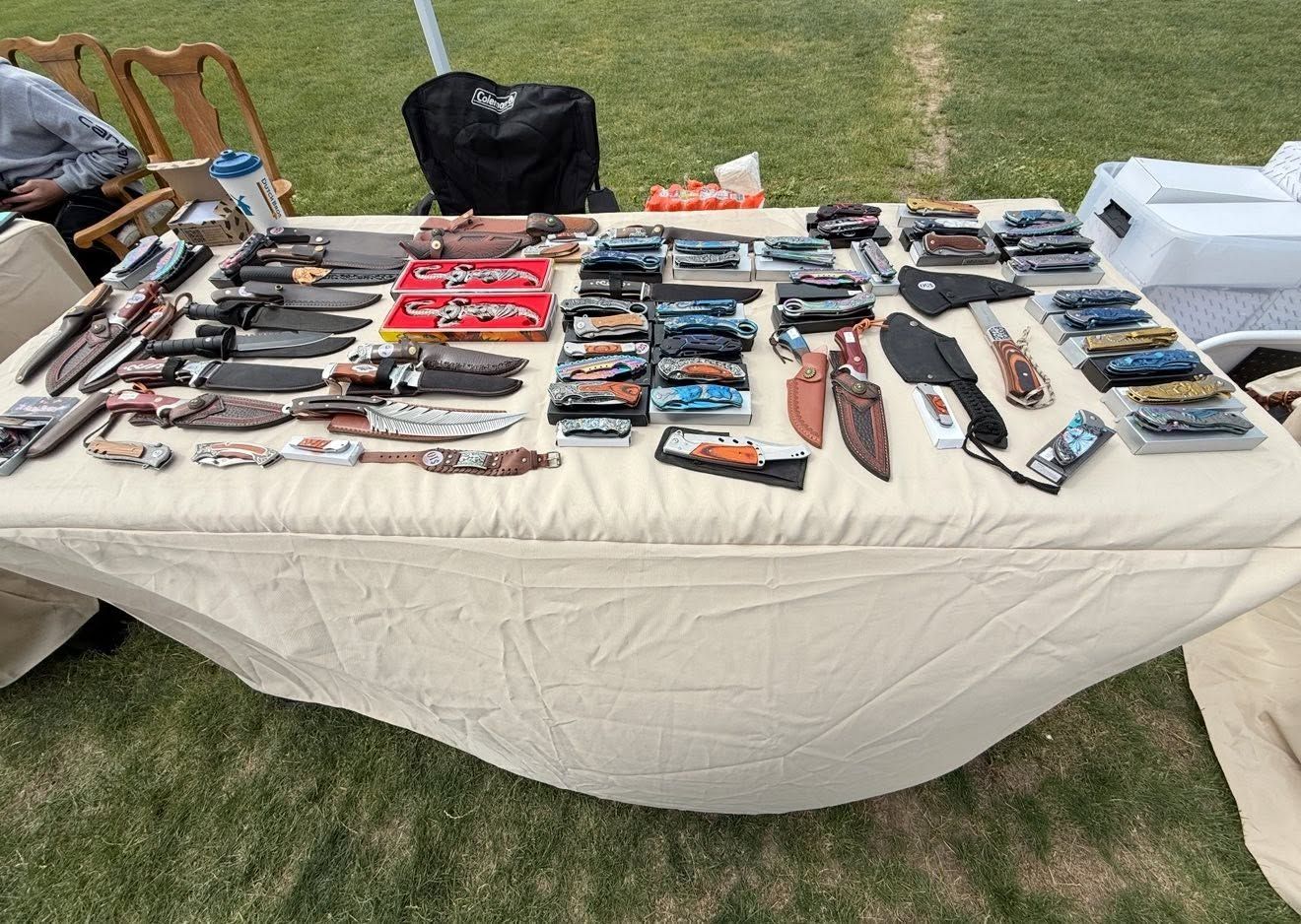 Assorted knives and multitools displayed on a table at an outdoor market