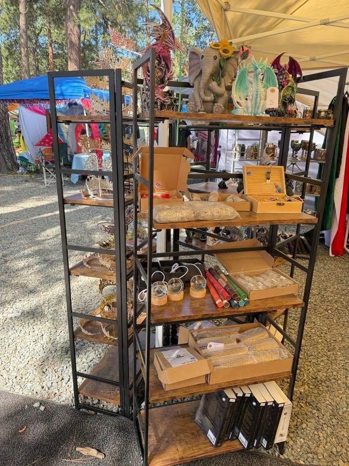 Outdoor market stall with wooden shelves displaying mugs, glassware, and small gifts under a canopy