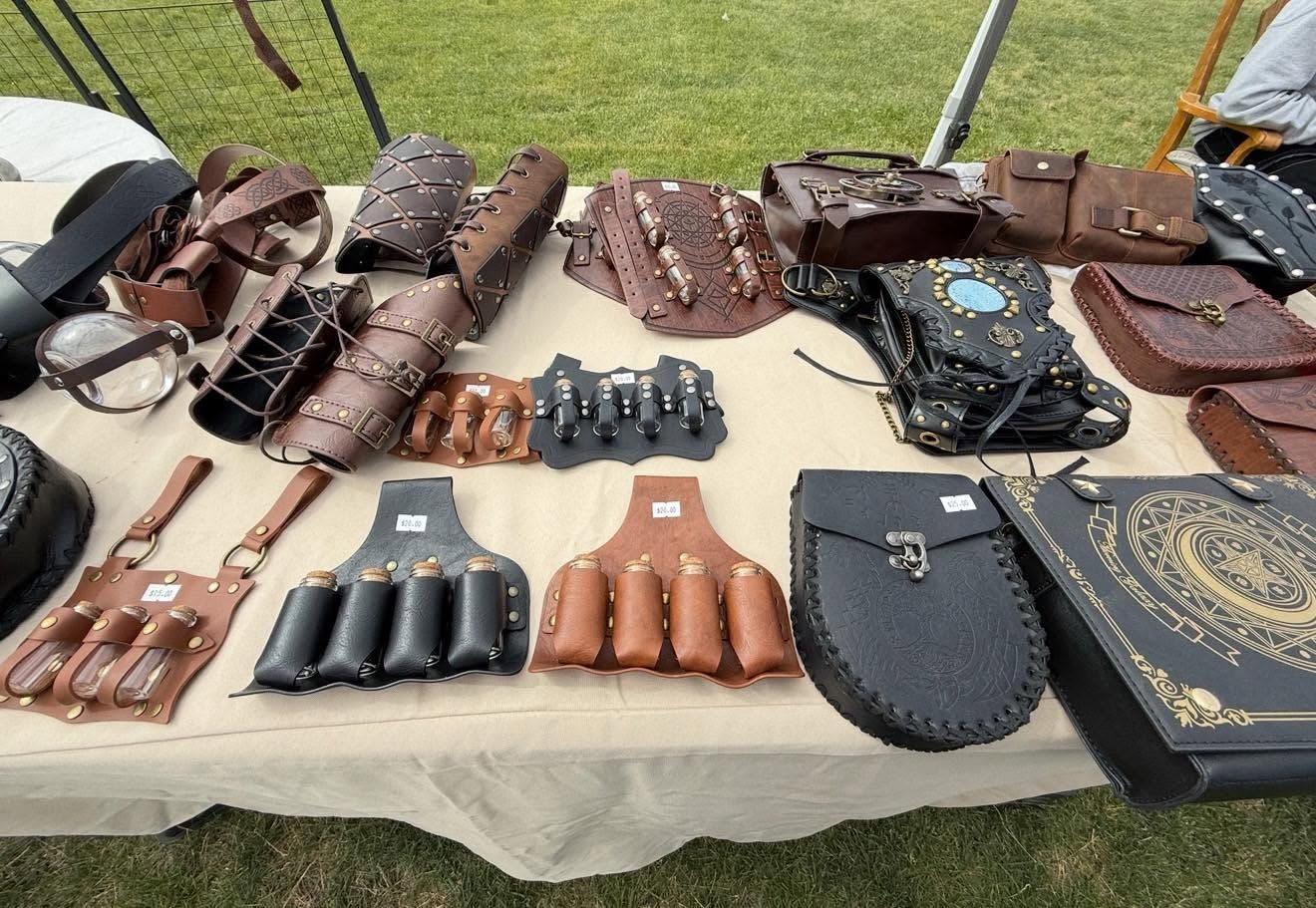 Leather knife sheaths and pouches displayed on cloth outdoors at a market stall