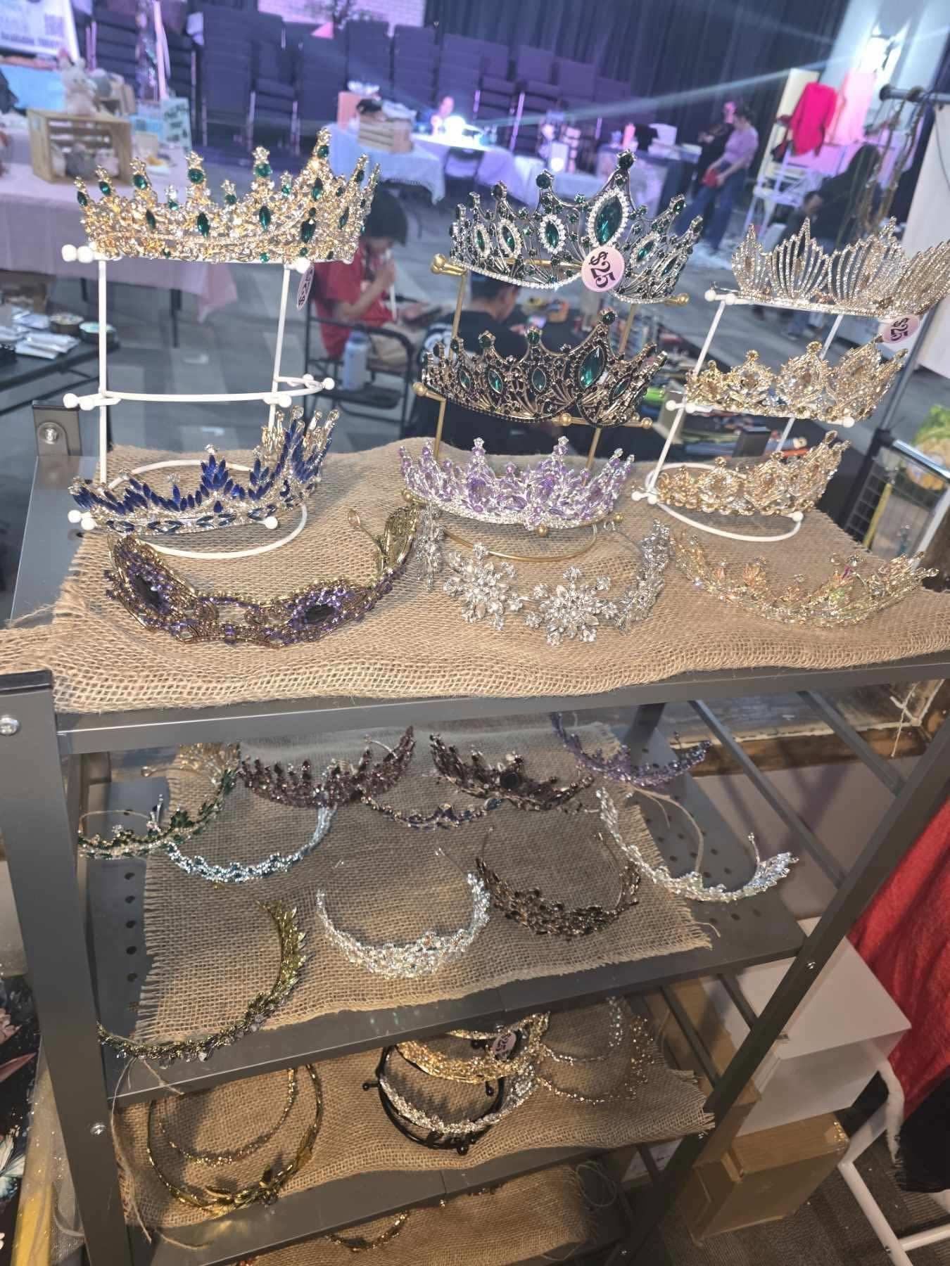 Display of ornate tiaras and jeweled headbands on a glass shelf in a shop.